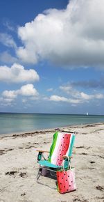 Deck chairs on beach against sky