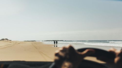 Person on beach against clear sky