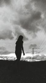 Silhouette of woman standing against cloudy sky