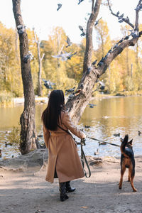 Rear view of woman with dog on riverbank