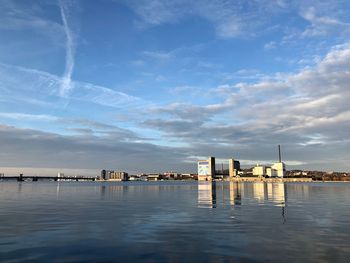 Factory by sea against sky in city