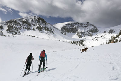 Rear view of people on snowcapped mountain against sky