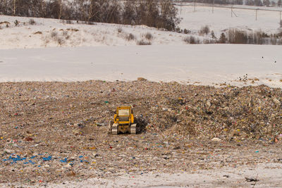 Earth mover working on field by during winter