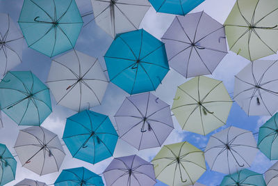 Low angle view of multi colored umbrellas hanging against sky