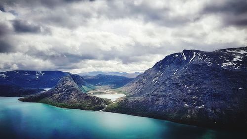 Scenic view of lake by snowcapped mountains against sky