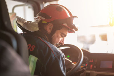 Rear view of man working in car