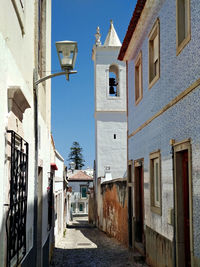 Narrow street amidst buildings against blue sky