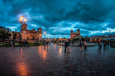 People at illuminated temple against sky in city