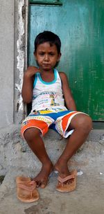 Portrait of cute girl sitting against wall