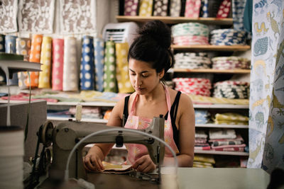 Woman sewing textile while working in fabric shop