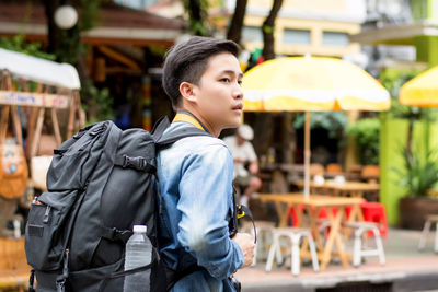 Young man with backpack looking away outdoors