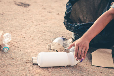 Cropped hand of person collecting garbage on sand