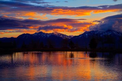 Scenic view of lake and mountains against orange sky