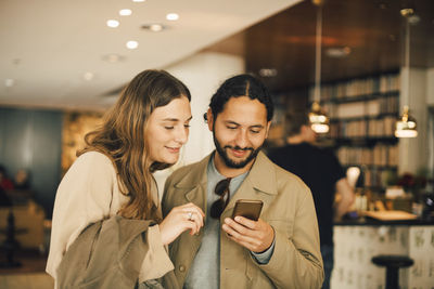 Couple using smart phone while standing in hotel