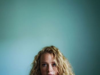 Portrait of beautiful young woman against blue wall