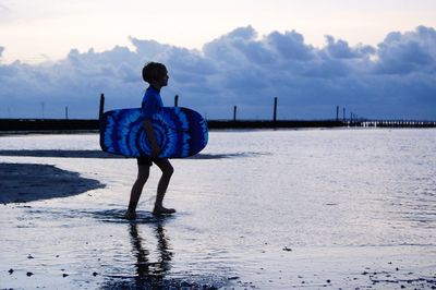 Rear view of woman standing on beach against sky