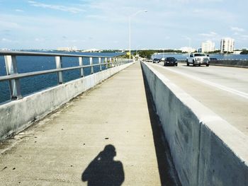 Shadow of person on bridge by lake