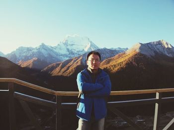 Confident man standing with arms crossed against mountains at observation point