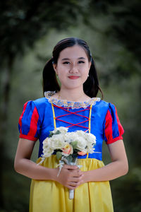 Portrait of young woman standing against trees