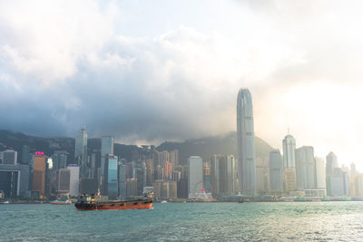 Sea by modern buildings against sky in city