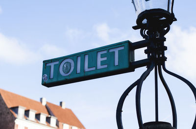 Low angle view of toilet sign against sky