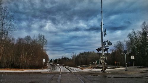 Road by bare trees against sky