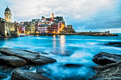 View of illuminated vernazza village reef and sea during at blue hour, five towns, liguria, italy