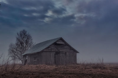 Houses on field against cloudy sky