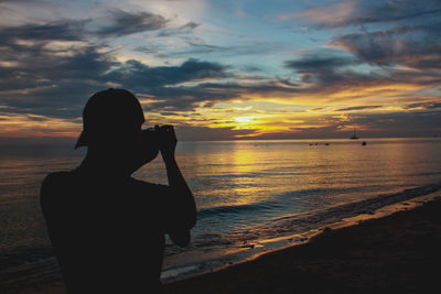 Rear view of woman looking at sea during sunset