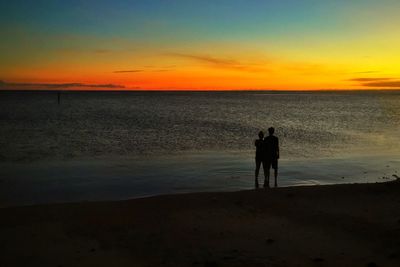 Rear view of silhouette man on beach against sky during sunset