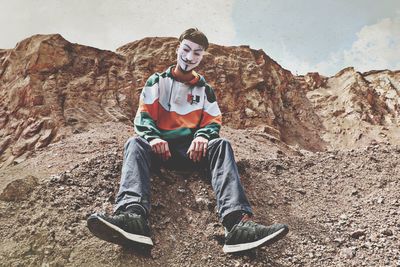 Portrait of young man sitting on rock