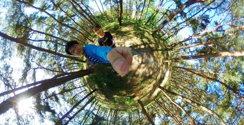 Low angle view of woman against trees against sky