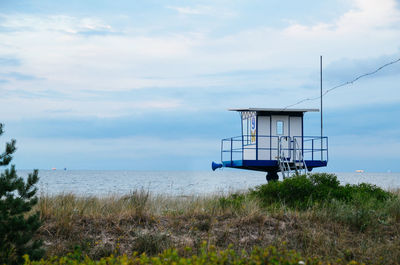 Lifeguard hut by baltic sea against cloudy sky