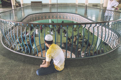 High angle view of man looking at people praying in mosque