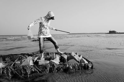 Rear view of man standing by sea against clear sky