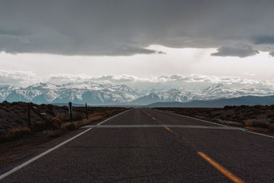 Road leading towards mountains against sky