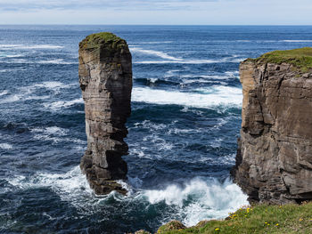 Scenic view of rocks on sea shore against sky