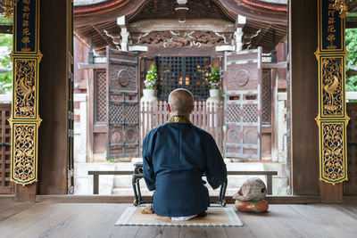 Rear view of man sitting in temple outside building