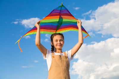 Girl alone launches a multicolored kite into sky.