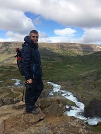 Full length portrait of man standing on rock against sky