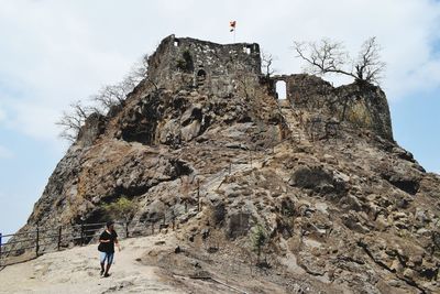 Low angle view of people on rock against sky