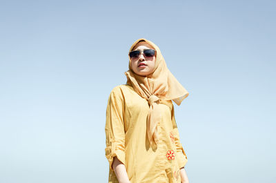 Woman wearing sunglasses and hijab against clear sky