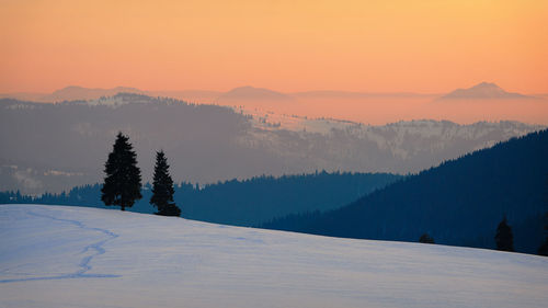 Scenic view of snow covered mountains against sky during sunset