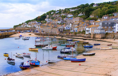 Boats moored at harbor by buildings in city