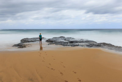 Rear view of person standing on beach against sky