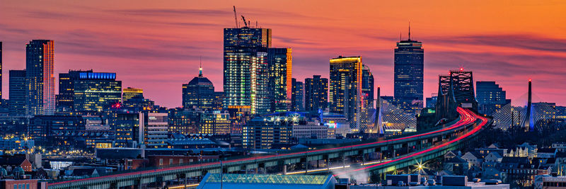 Illuminated buildings in city at sunset