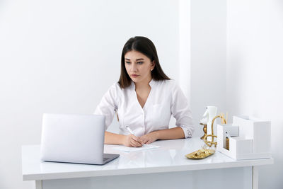 Portrait of young businesswoman using laptop while sitting on table