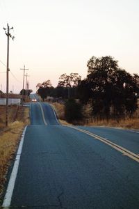 Road by trees against clear sky