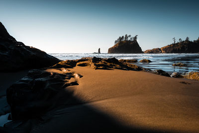 Rock formations on beach against clear sky