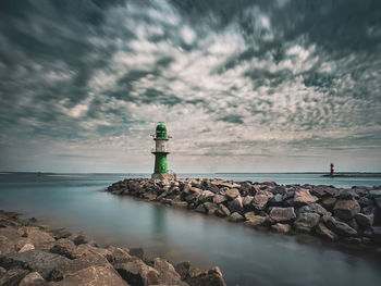 Lighthouse by sea against sky